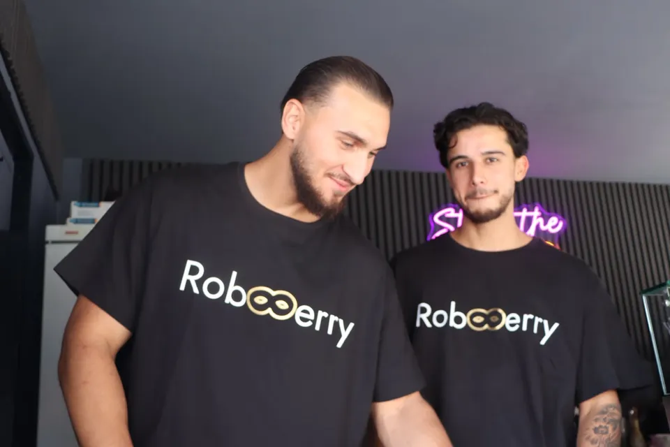 Zwei Teammitglieder im RobBerry-Shirt an der Theke, im Hintergrund der Neonschriftzug